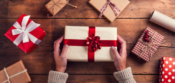 Man holding Christmas presents laid on a wooden table background